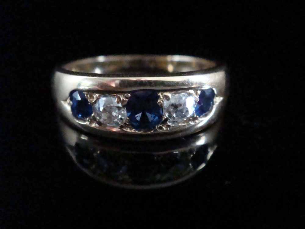 A Victorian 18ct yellow gold gypsy ring set with five alternating blue sapphires and old cut diamonds flush inside a wide band.