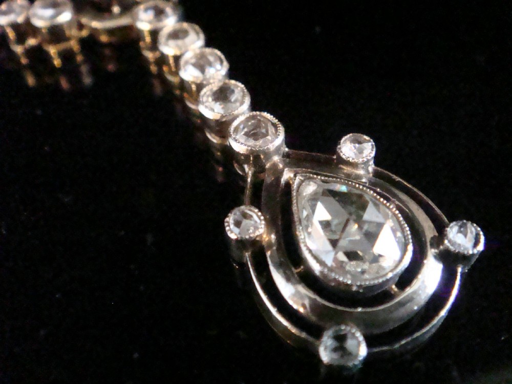An Edwardian gold link chain supporting an articulated drop pendant set with multiple bezel-set rose cut diamonds terminating in a pear-shaped drop. View II