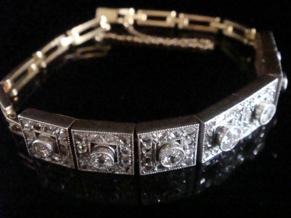 An Art Deco platinum and diamond bracelet composed of square articulated panel links set with central old cut diamonds and millegrain borders. View III