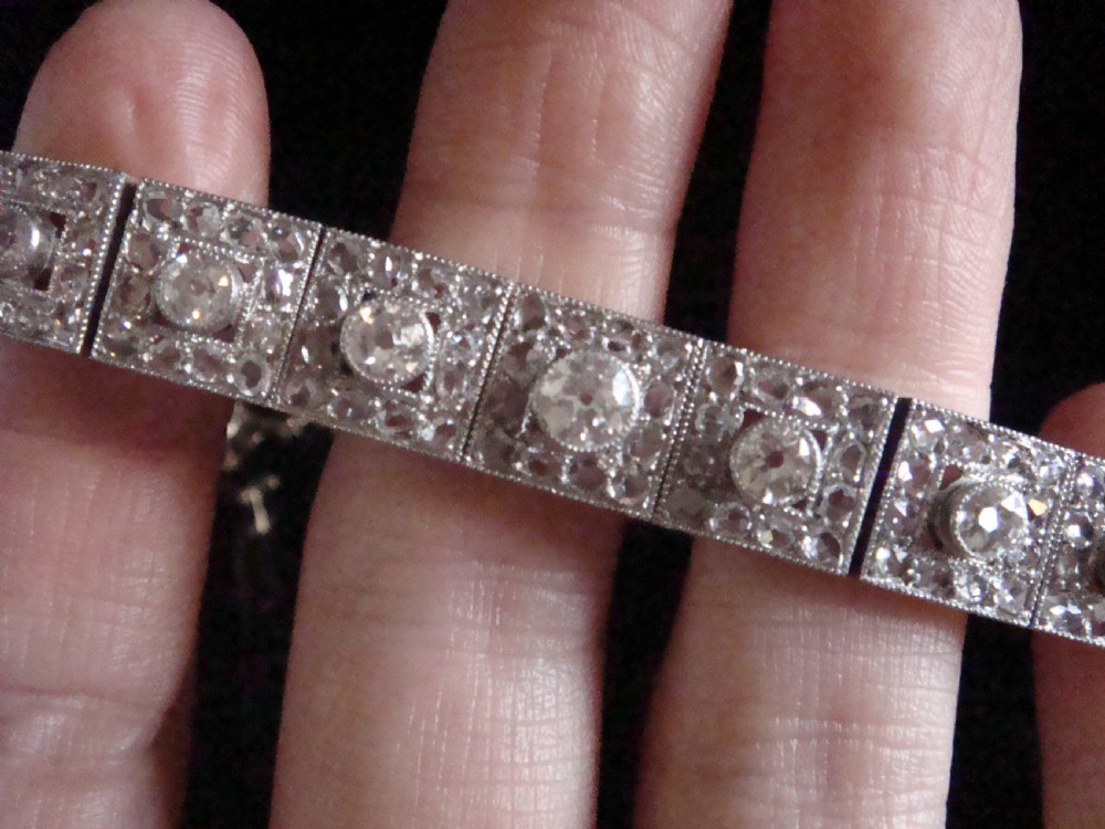 An Art Deco platinum and diamond bracelet composed of square articulated panel links set with central old cut diamonds and millegrain borders. View IV