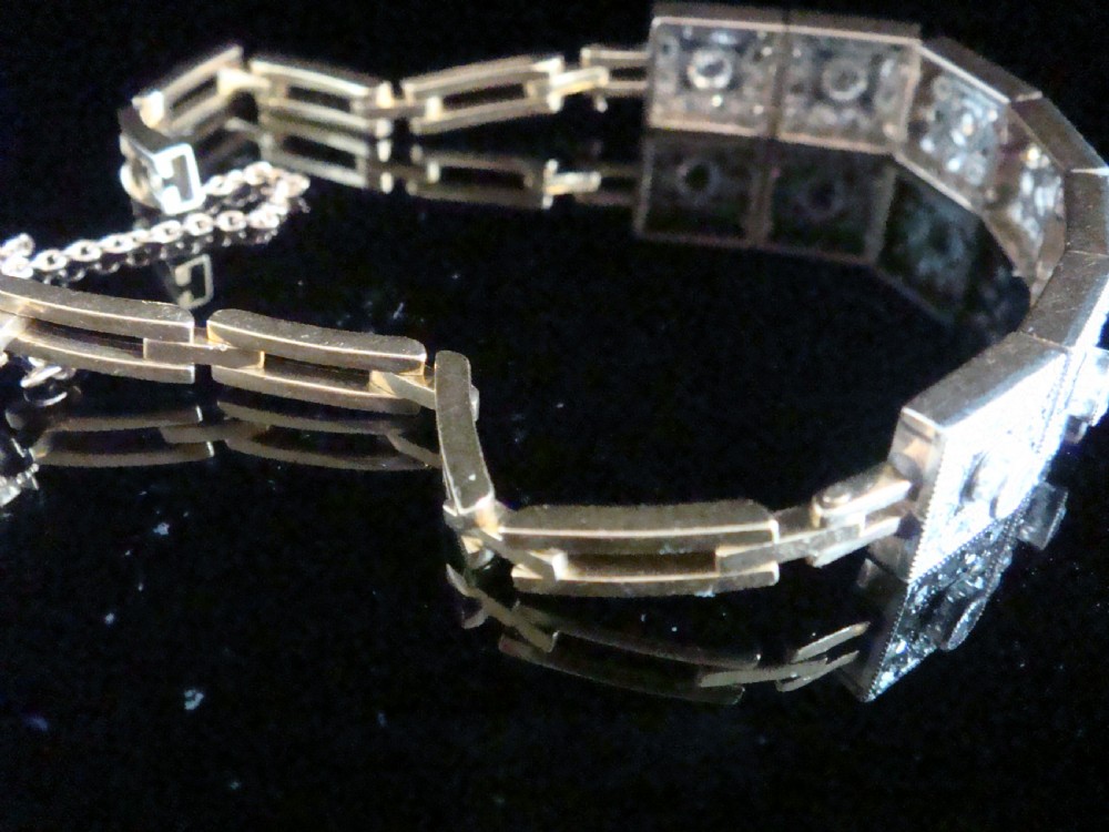 An Art Deco platinum and diamond bracelet composed of square articulated panel links set with central old cut diamonds and millegrain borders. View V