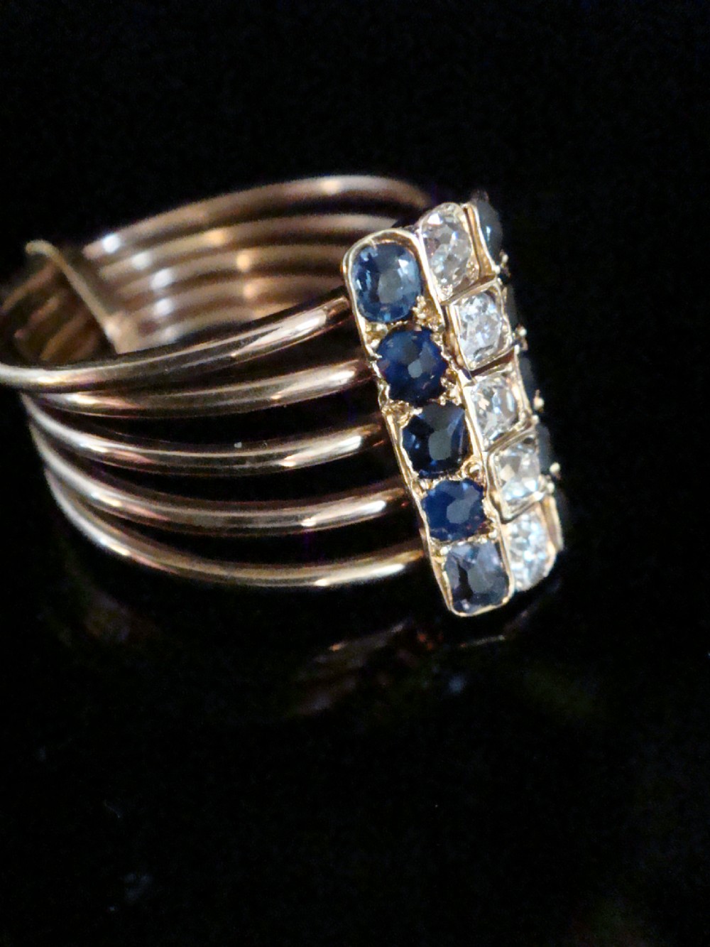 An Edwardian five-row rose gold harem ring featuring a vertical rectangular bar set with central diamonds flanked by blue sapphires. View II