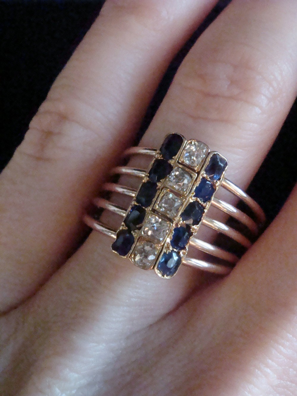 An Edwardian five-row rose gold harem ring featuring a vertical rectangular bar set with central diamonds flanked by blue sapphires. View IV
