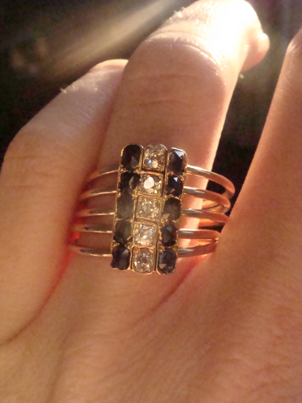 An Edwardian five-row rose gold harem ring featuring a vertical rectangular bar set with central diamonds flanked by blue sapphires. View VI