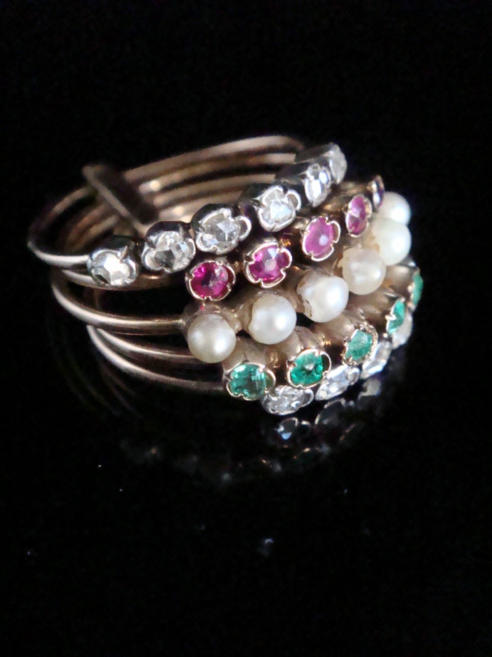 An Edwardian multi-band 18ct rose gold harem ring set with individual rows of diamonds, rubies, seed pearls, and emeralds. View IV