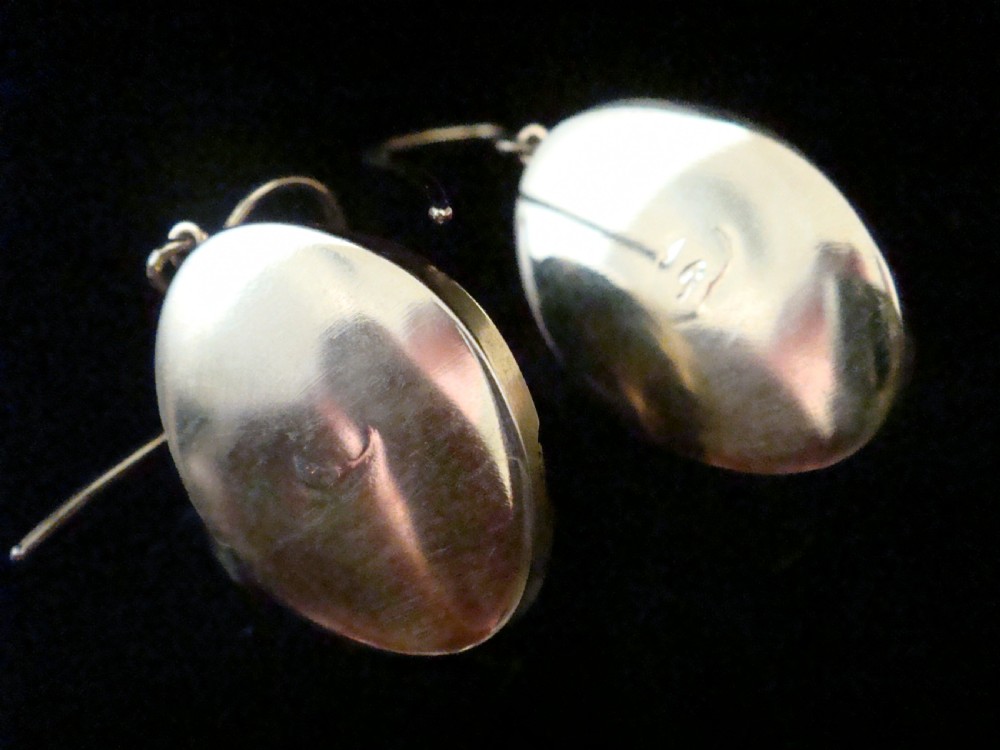 A pair of Victorian 15ct gold drop earrings featuring oval cabochon garnets within textured golden frames with wire hooks. View VI