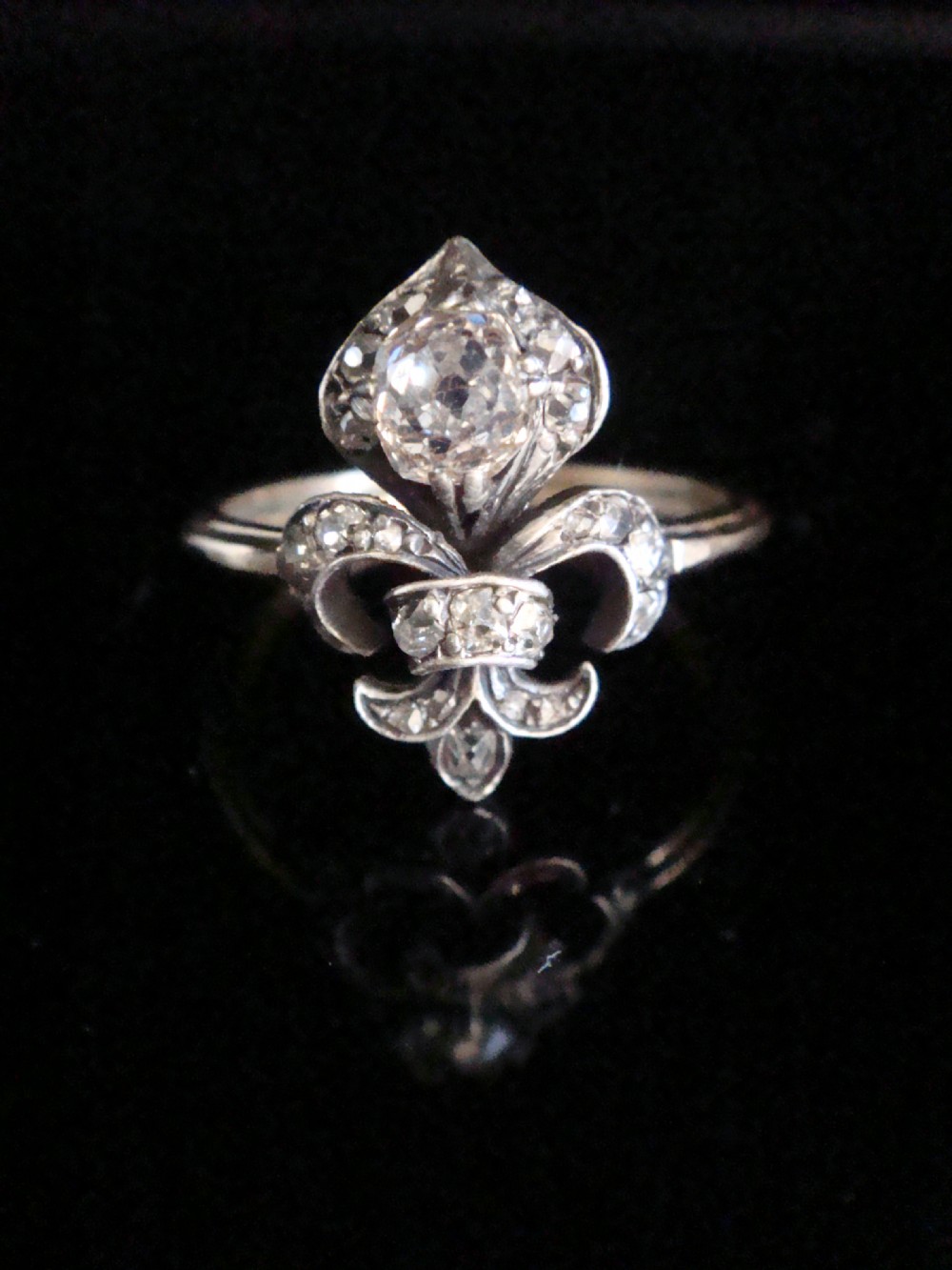 A Georgian silver and gold ring featuring a central fleur-de-lis motif set with old cut diamonds.