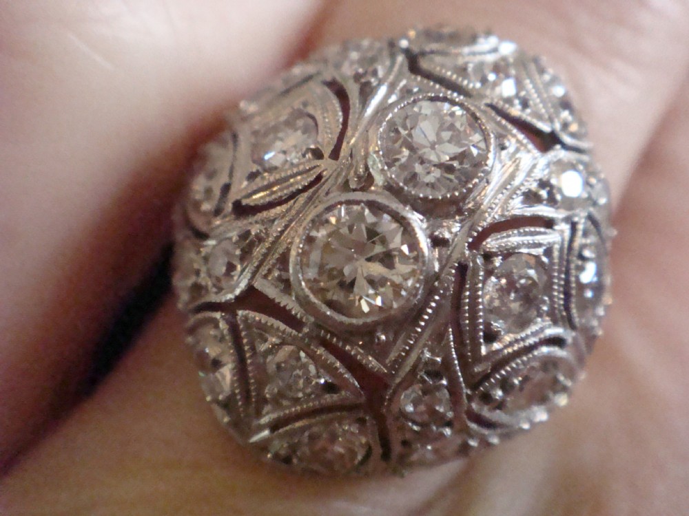 An Art Deco platinum bombe ring set with multiple transitional-cut diamonds in a rounded geometric pattern with millegrain detailing. View IV