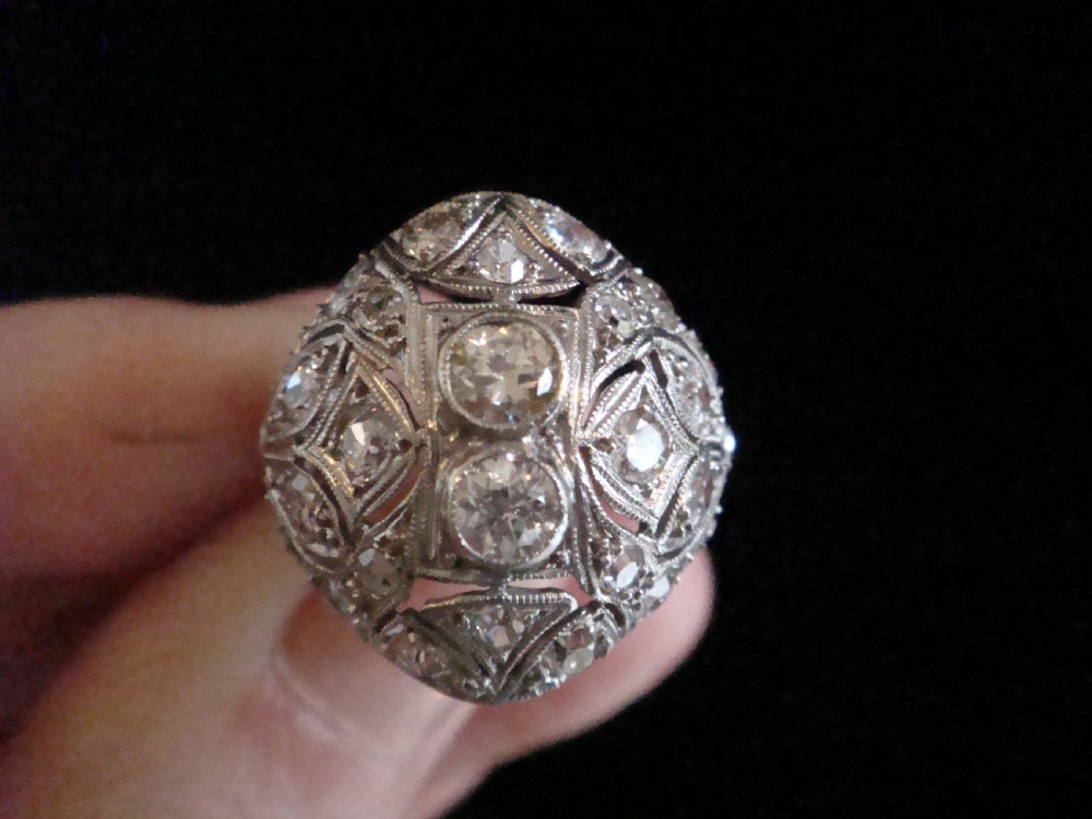An Art Deco platinum bombe ring set with multiple transitional-cut diamonds in a rounded geometric pattern with millegrain detailing. View V
