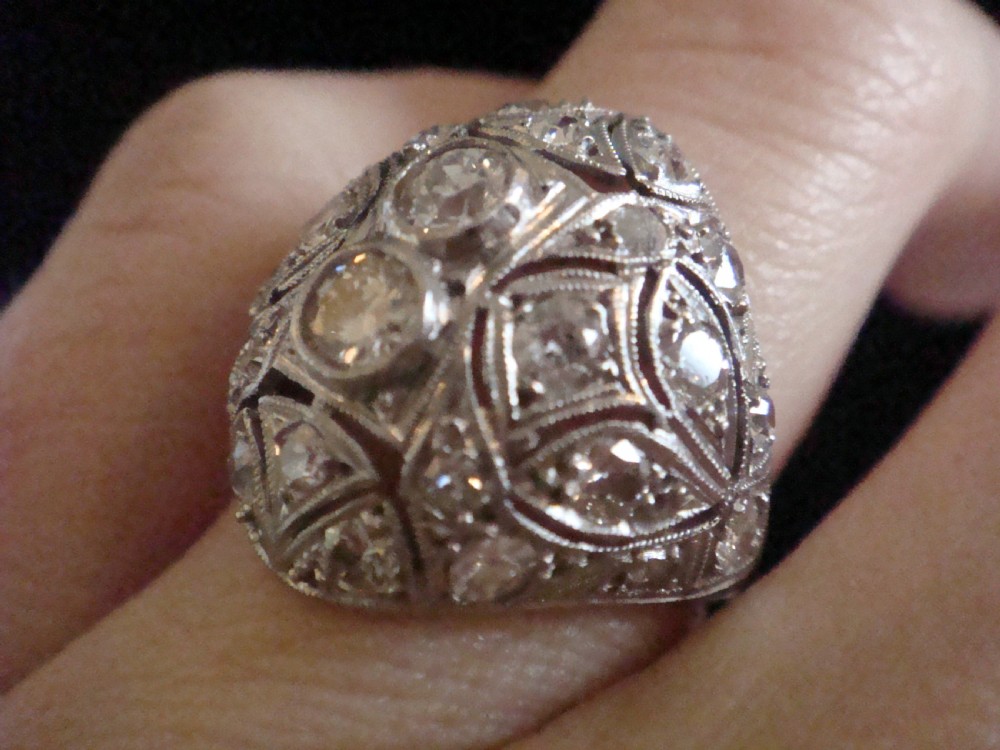 An Art Deco platinum bombe ring set with multiple transitional-cut diamonds in a rounded geometric pattern with millegrain detailing. View VI
