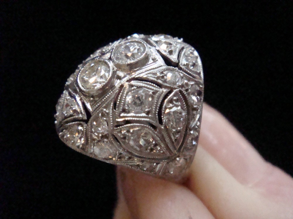 An Art Deco platinum bombe ring set with multiple transitional-cut diamonds in a rounded geometric pattern with millegrain detailing. View VII