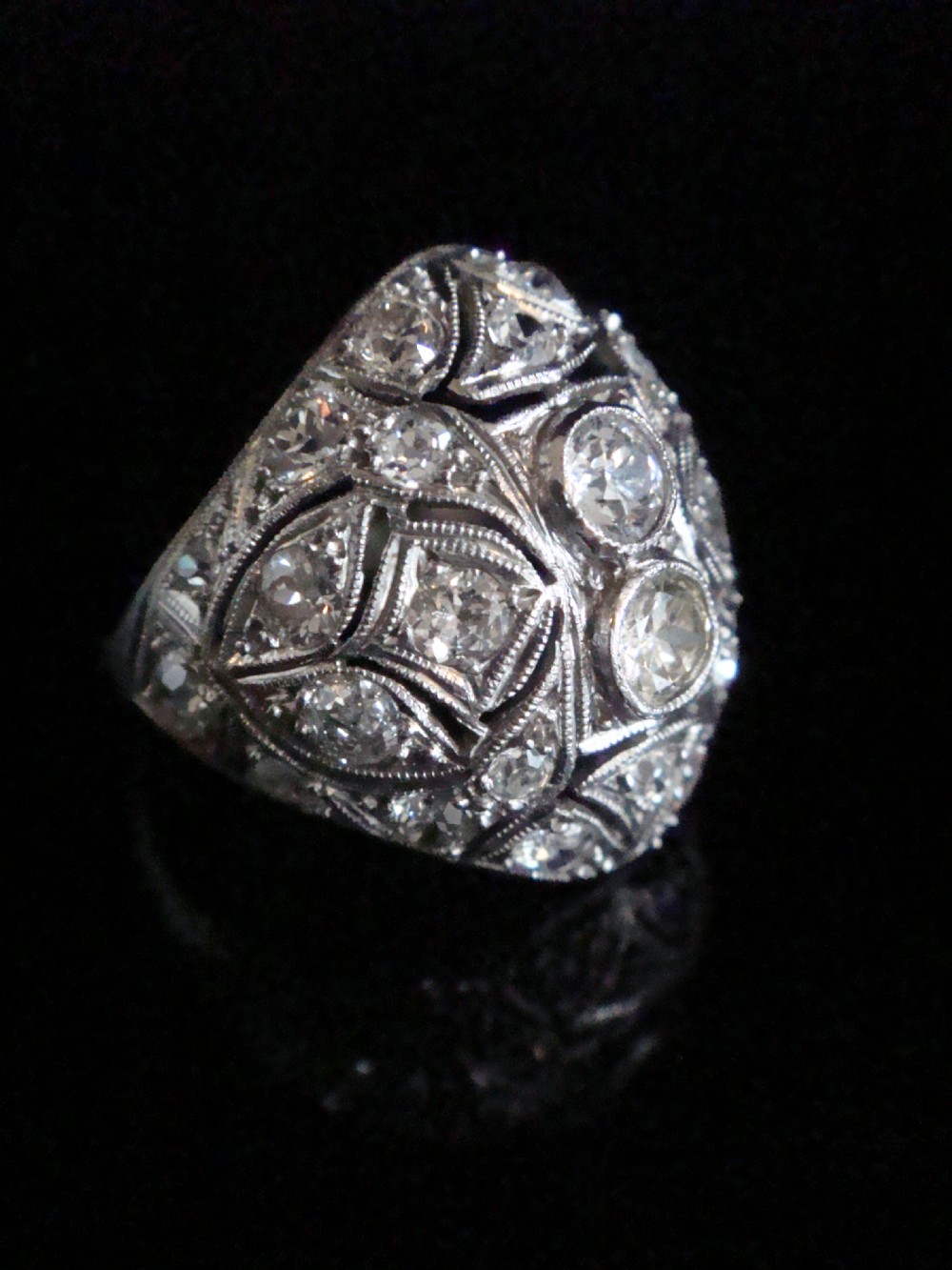 An Art Deco platinum bombe ring set with multiple transitional-cut diamonds in a rounded geometric pattern with millegrain detailing. View VIII