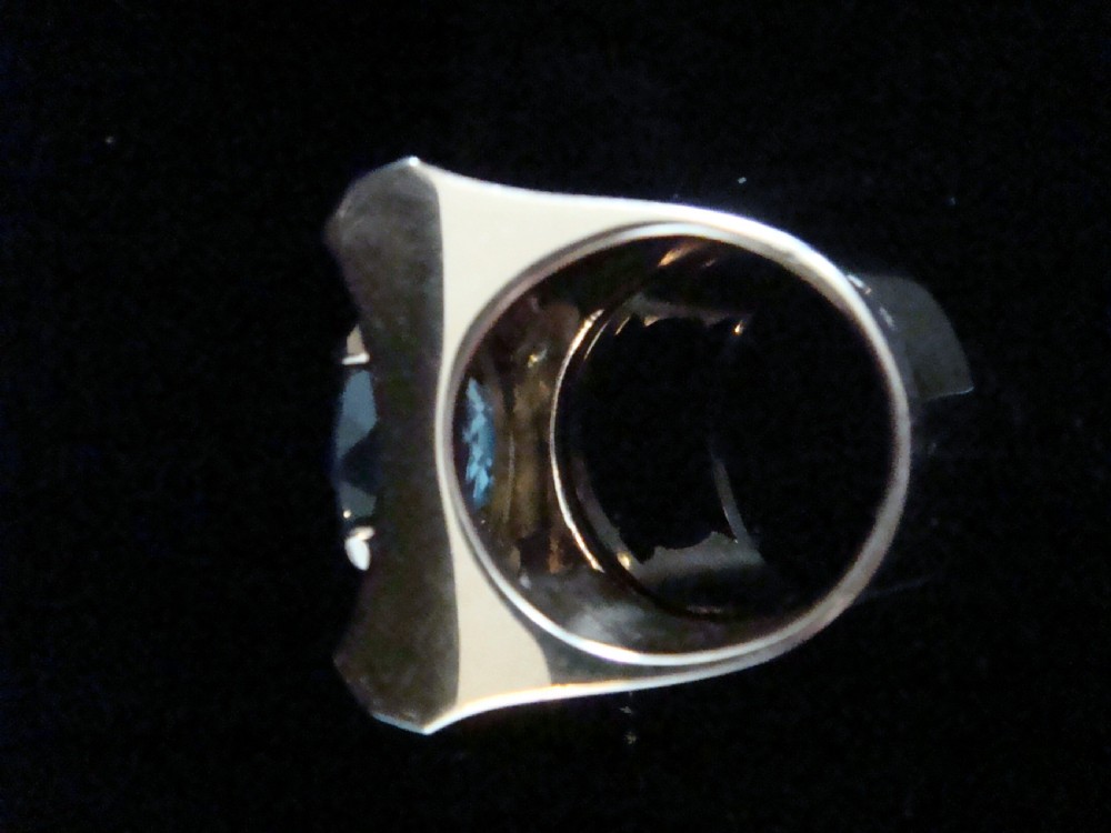 An antique French Tank ring featuring an oval faceted light blue topaz set in gold, framed by broad platinum shoulders set with small accent diamonds. View III