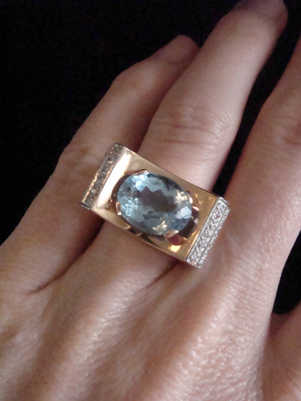 An antique French Tank ring featuring an oval faceted light blue topaz set in gold, framed by broad platinum shoulders set with small accent diamonds. View V