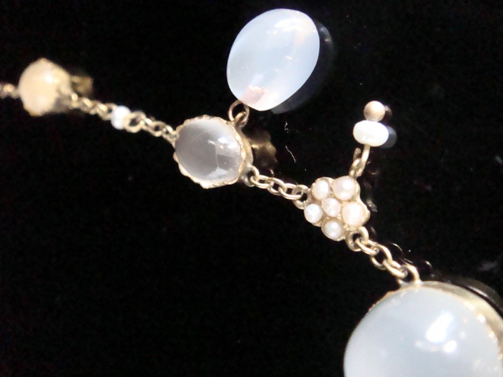 An Edwardian gold lavaliere necklace set with oval cabochon moonstones, seed pearl clusters, and a central drop pendant with diamond detail. View III