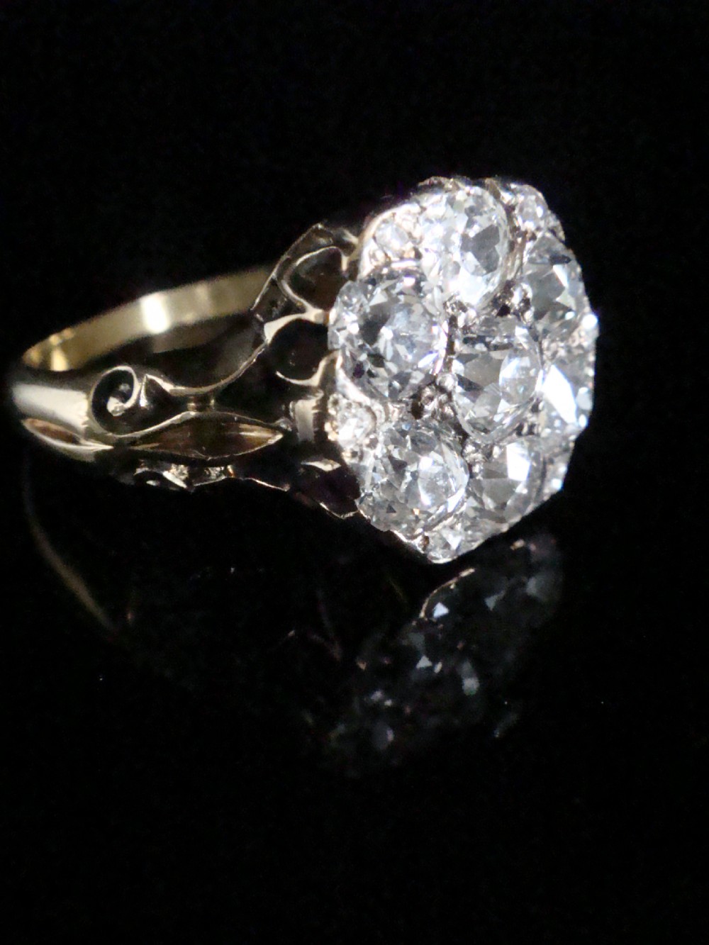 Victorian 18ct yellow gold ring featuring a multi-diamond cluster head and ornate scrollwork shoulders.