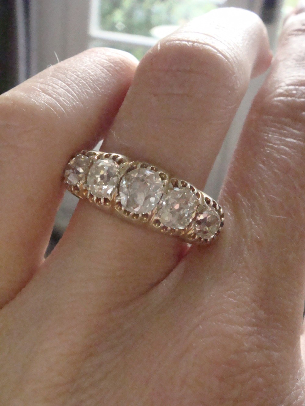 An early Victorian 18ct yellow gold ring featuring five graduated old-cut diamonds set horizontally along a carved gallery. View VI