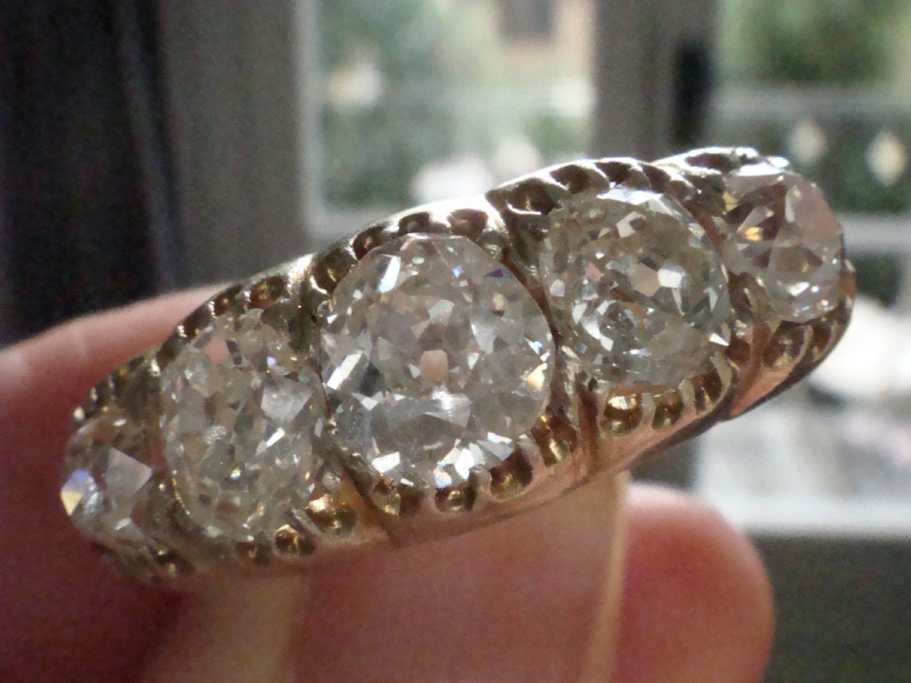 An early Victorian 18ct yellow gold ring featuring five graduated old-cut diamonds set horizontally along a carved gallery. View VII