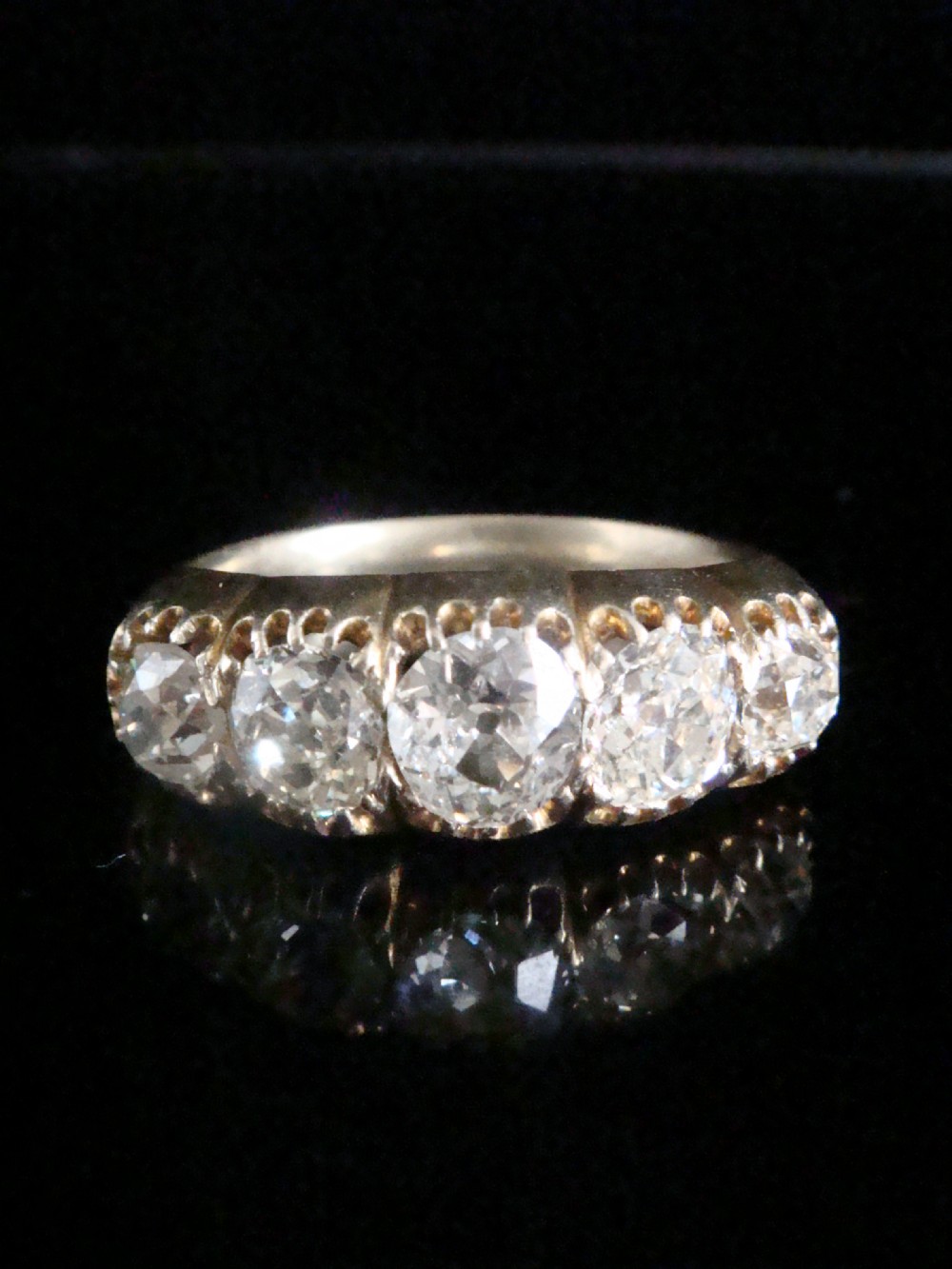 An early Victorian 18ct yellow gold ring featuring five graduated old-cut diamonds set horizontally along a carved gallery. View VIII