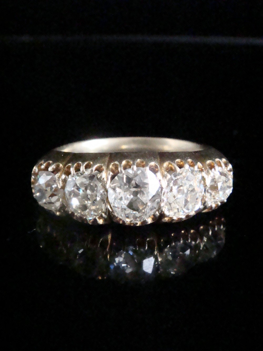 An early Victorian 18ct yellow gold ring featuring five graduated old-cut diamonds set horizontally along a carved gallery. View IX