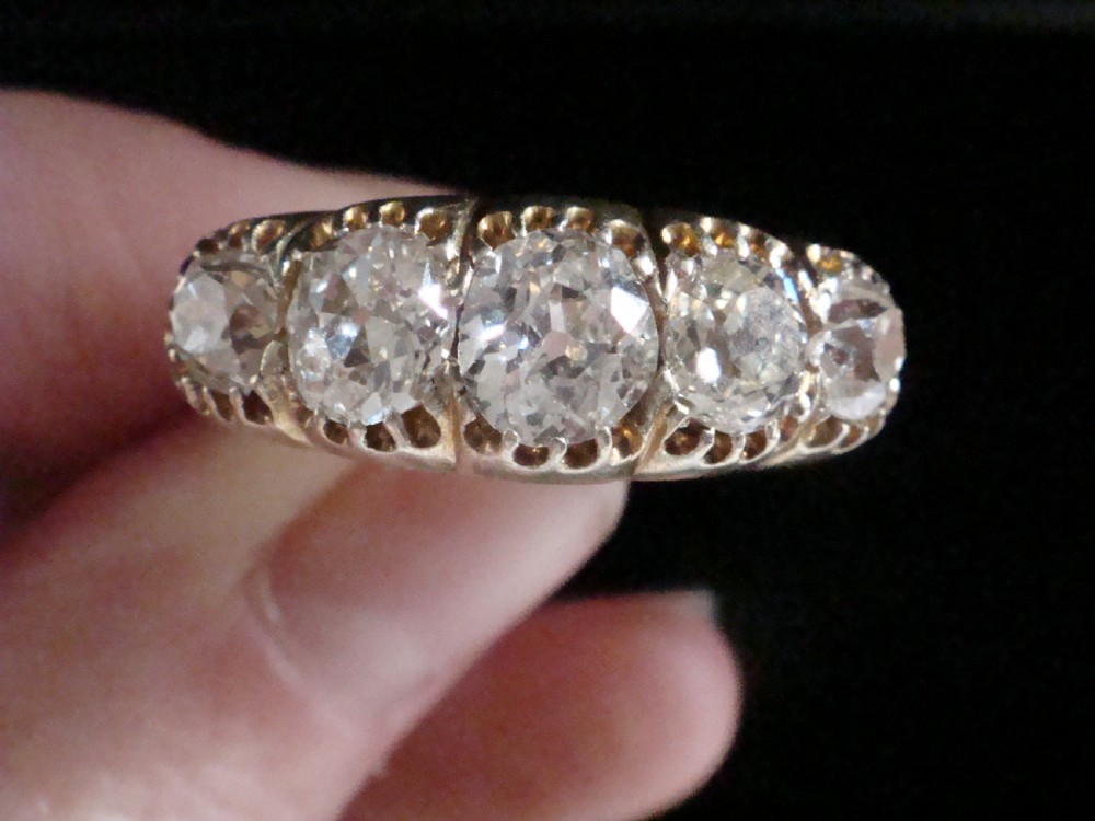 An early Victorian 18ct yellow gold ring featuring five graduated old-cut diamonds set horizontally along a carved gallery. View X