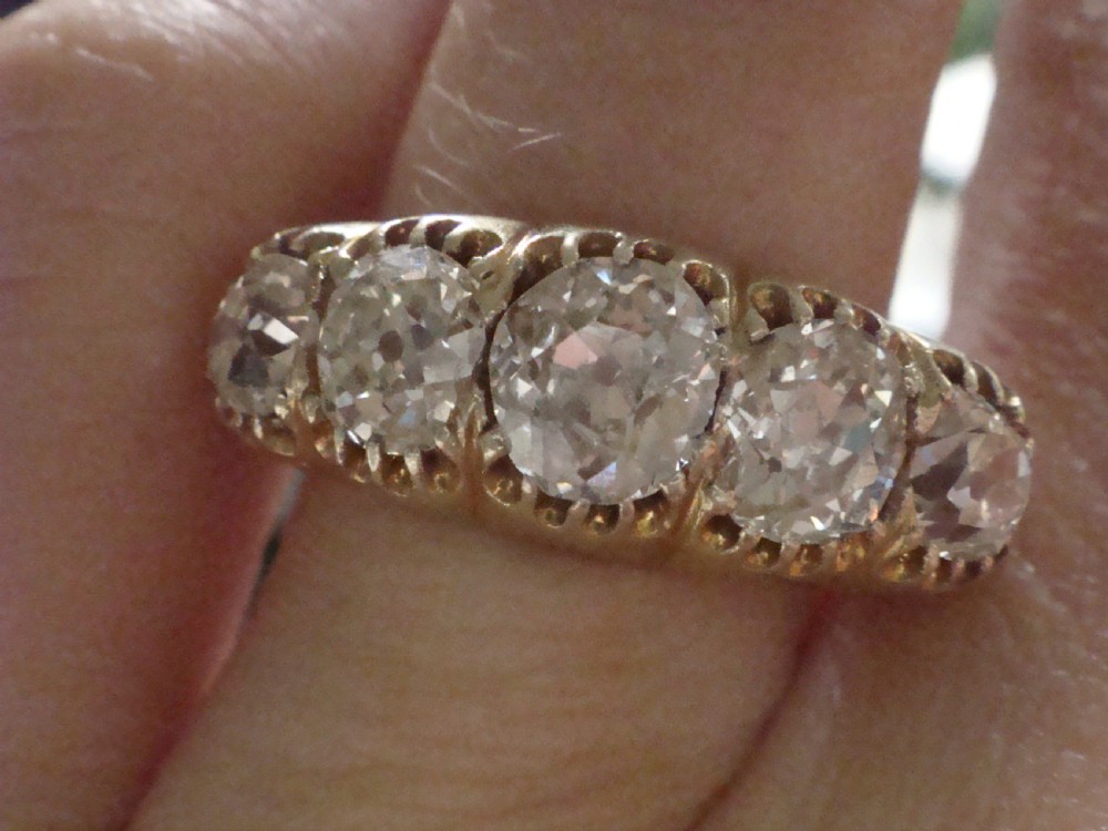 An early Victorian 18ct yellow gold ring featuring five graduated old-cut diamonds set horizontally along a carved gallery. View XI