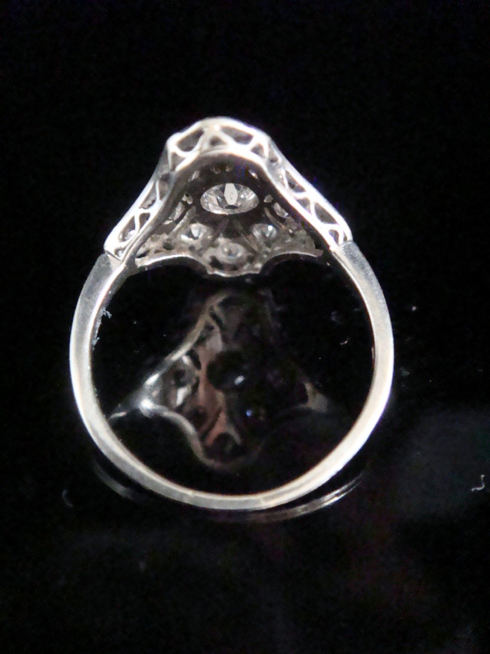 An Edwardian platinum dress ring featuring a central old cut diamond surrounded by geometric diamond-paved sections with millegrain edging. View II