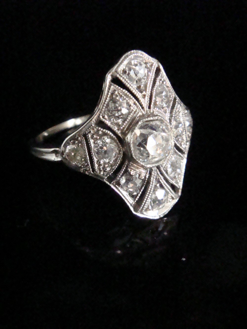 An Edwardian platinum dress ring featuring a central old cut diamond surrounded by geometric diamond-paved sections with millegrain edging. View III