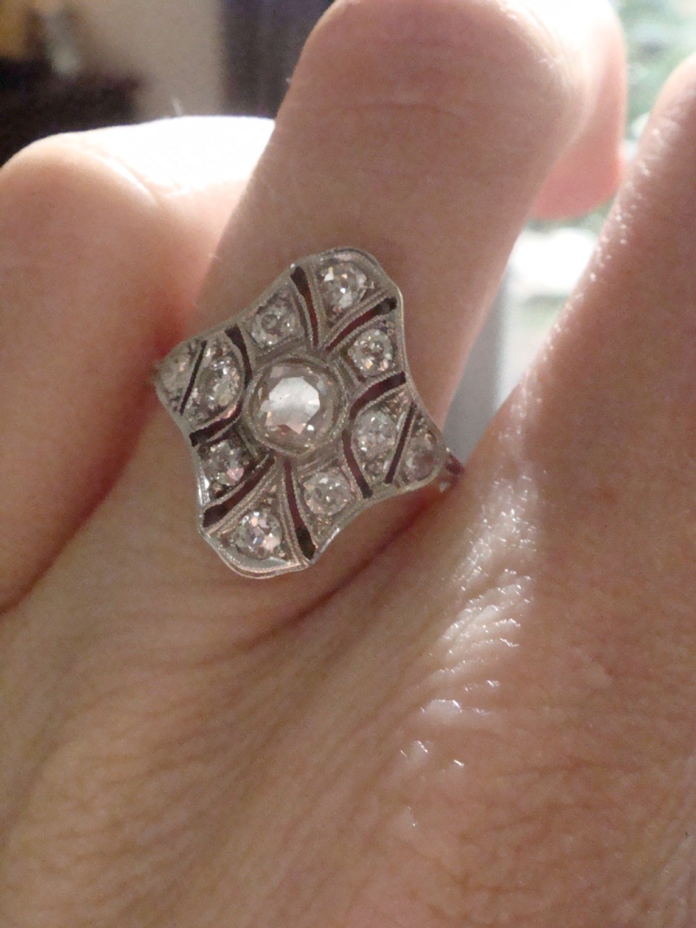 An Edwardian platinum dress ring featuring a central old cut diamond surrounded by geometric diamond-paved sections with millegrain edging. View VI