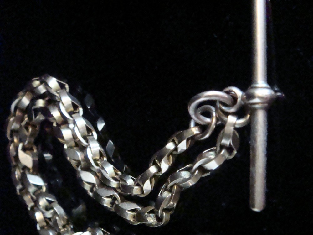 An Edwardian 9ct rose gold Albert chain featuring fancy interlocking links, dual dog clips, and a T-bar attachment. View II