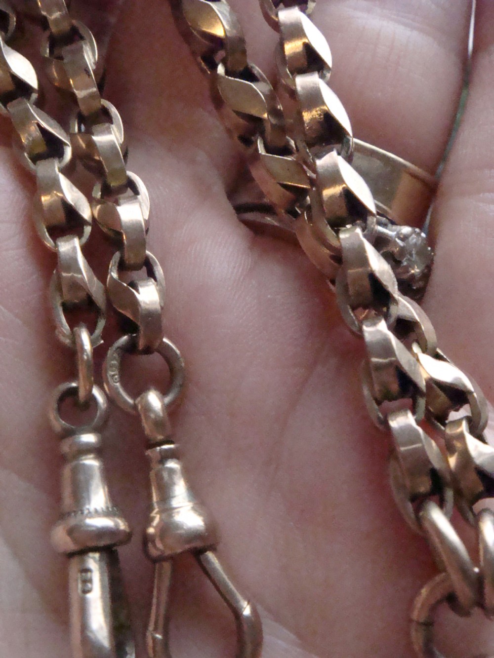 An Edwardian 9ct rose gold Albert chain featuring fancy interlocking links, dual dog clips, and a T-bar attachment. View III