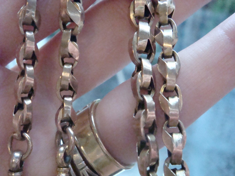 An Edwardian 9ct rose gold Albert chain featuring fancy interlocking links, dual dog clips, and a T-bar attachment. View VI