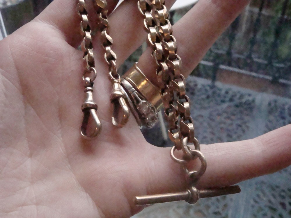 An Edwardian 9ct rose gold Albert chain featuring fancy interlocking links, dual dog clips, and a T-bar attachment. View VII