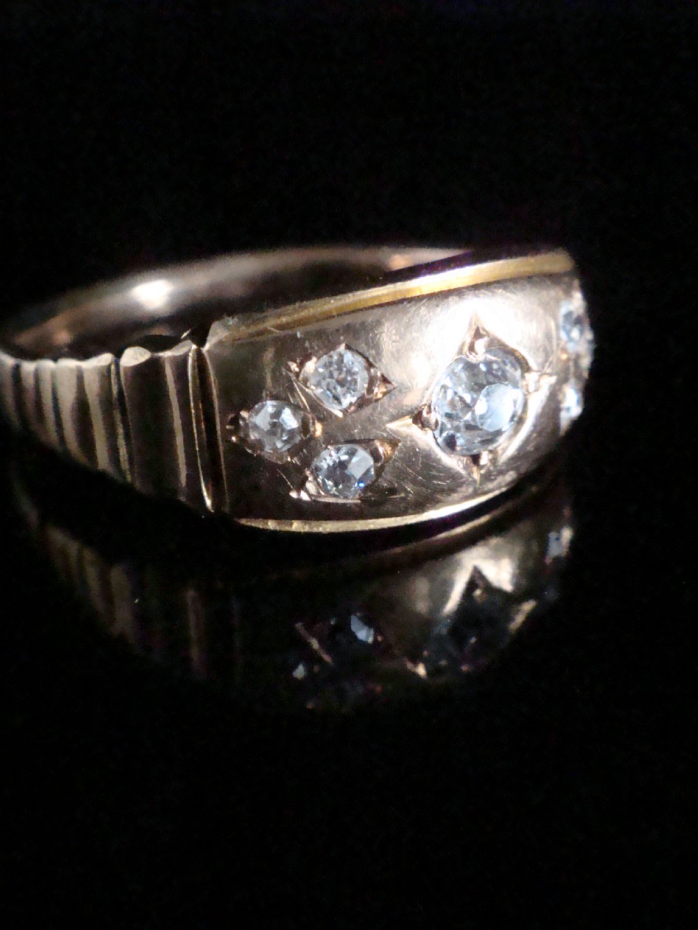 A Victorian 18ct yellow gold band featuring a central old cut diamond flanked by smaller flush-set diamonds in star-engraved settings. View II