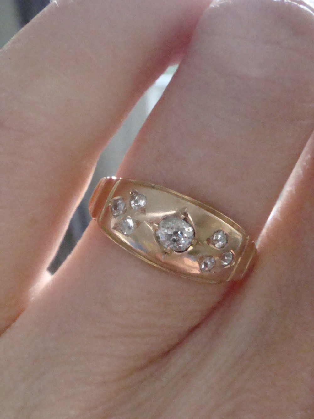 A Victorian 18ct yellow gold band featuring a central old cut diamond flanked by smaller flush-set diamonds in star-engraved settings. View IV
