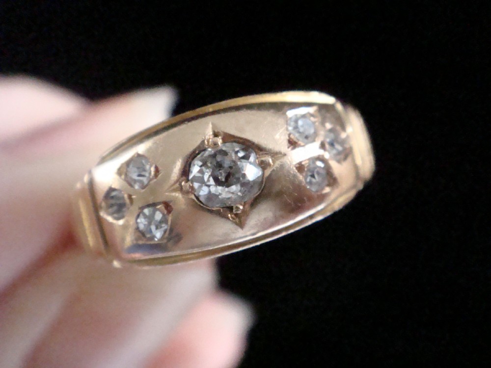 A Victorian 18ct yellow gold band featuring a central old cut diamond flanked by smaller flush-set diamonds in star-engraved settings. View V