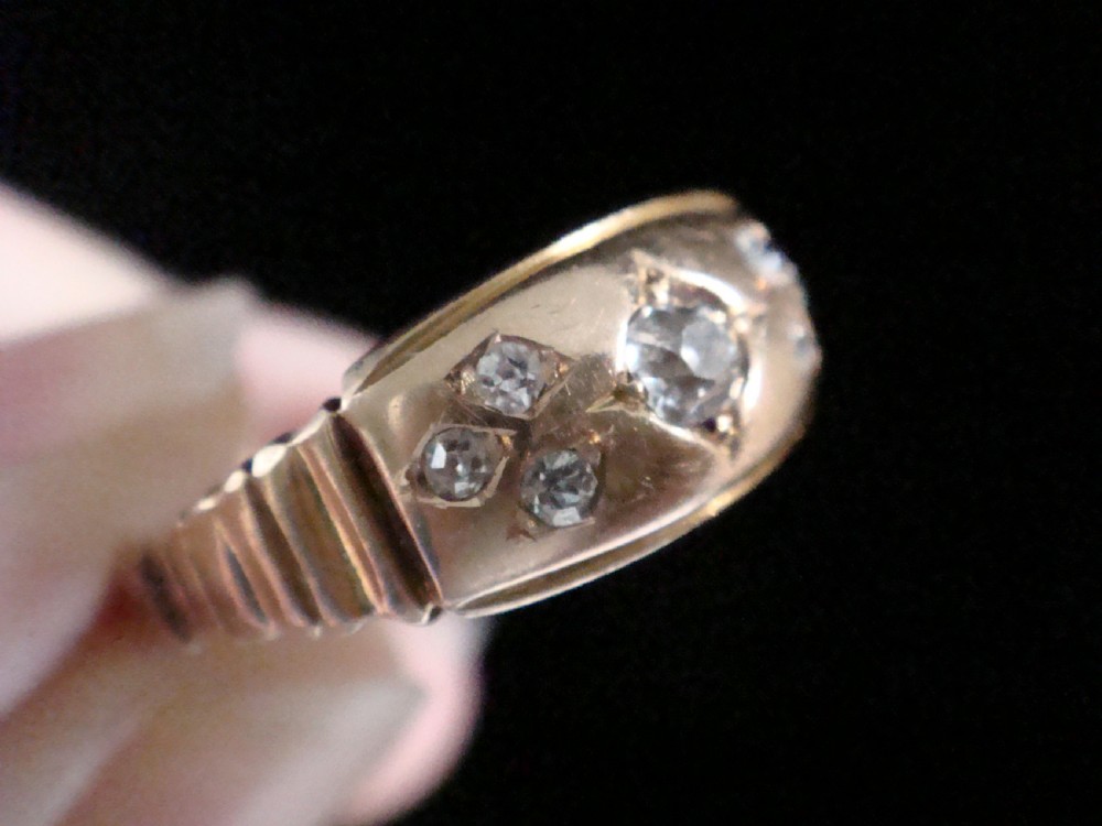 A Victorian 18ct yellow gold band featuring a central old cut diamond flanked by smaller flush-set diamonds in star-engraved settings. View VI