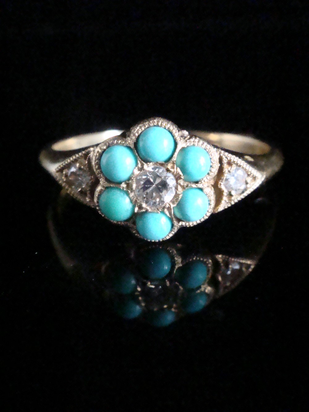 A Victorian 18ct yellow gold cluster ring featuring a central diamond surrounded by six turquoise cabochons with milgrain-detailed shoulders. View II