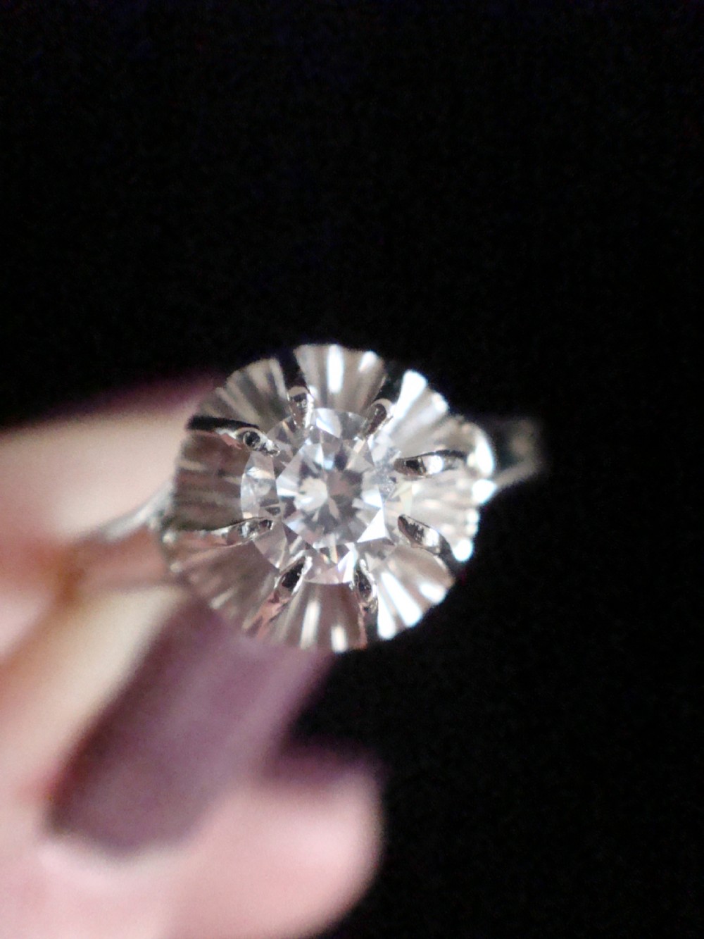 A vintage 18ct white gold solitaire ring featuring a central round diamond set within a fluted sunburst surround. View II
