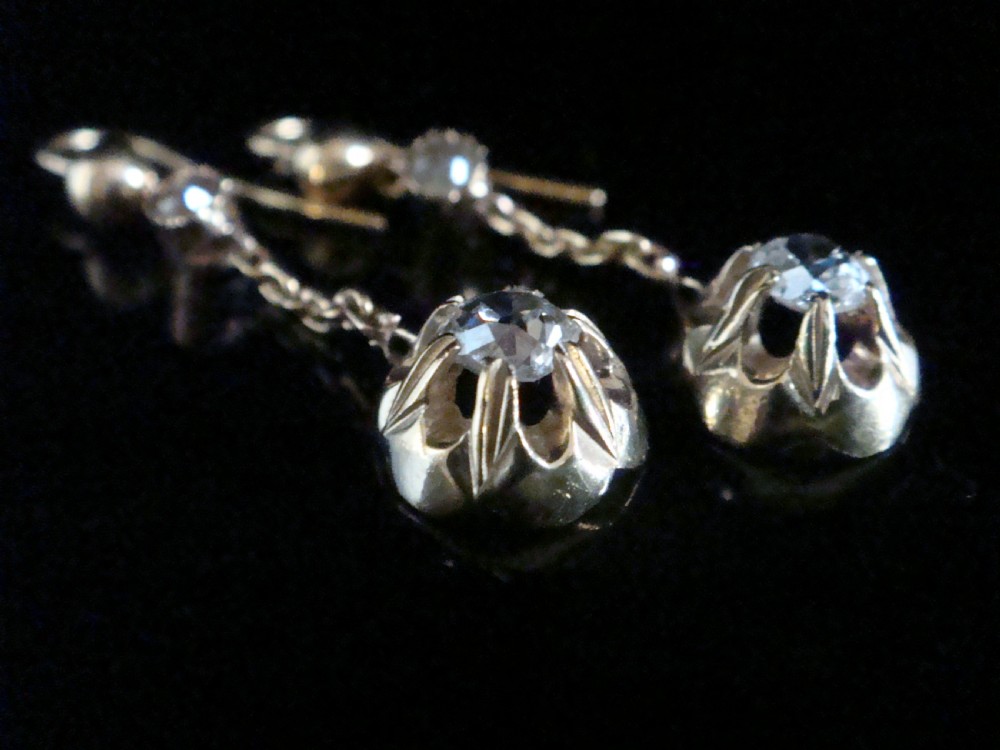 Victorian 18ct yellow gold drop earrings featuring old cut diamonds set within starburst crimped collet settings suspended from fine chains. View IV
