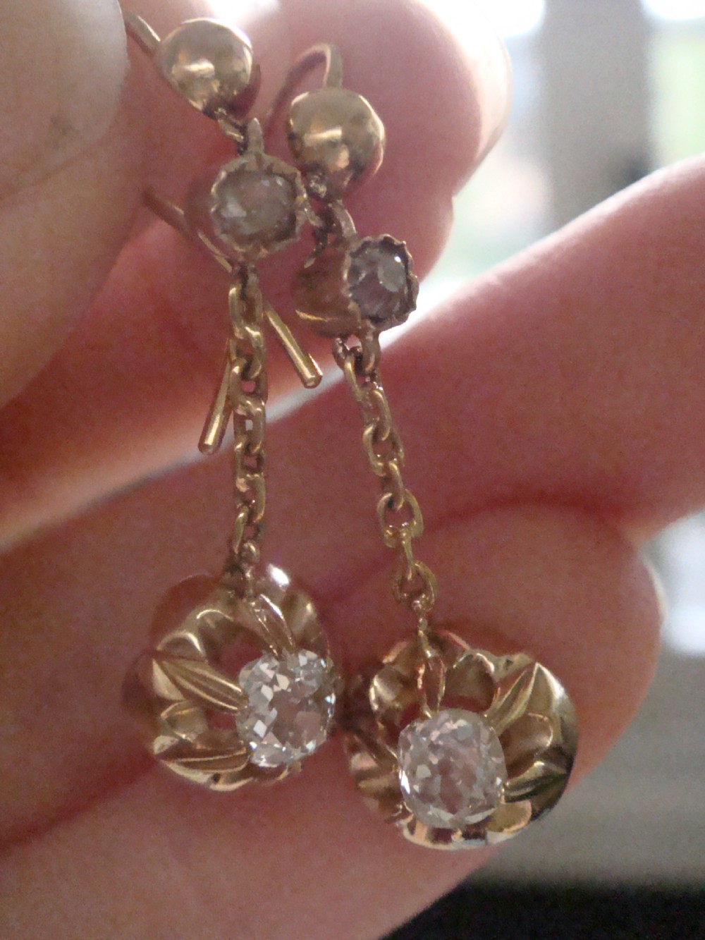 Victorian 18ct yellow gold drop earrings featuring old cut diamonds set within starburst crimped collet settings suspended from fine chains. View V