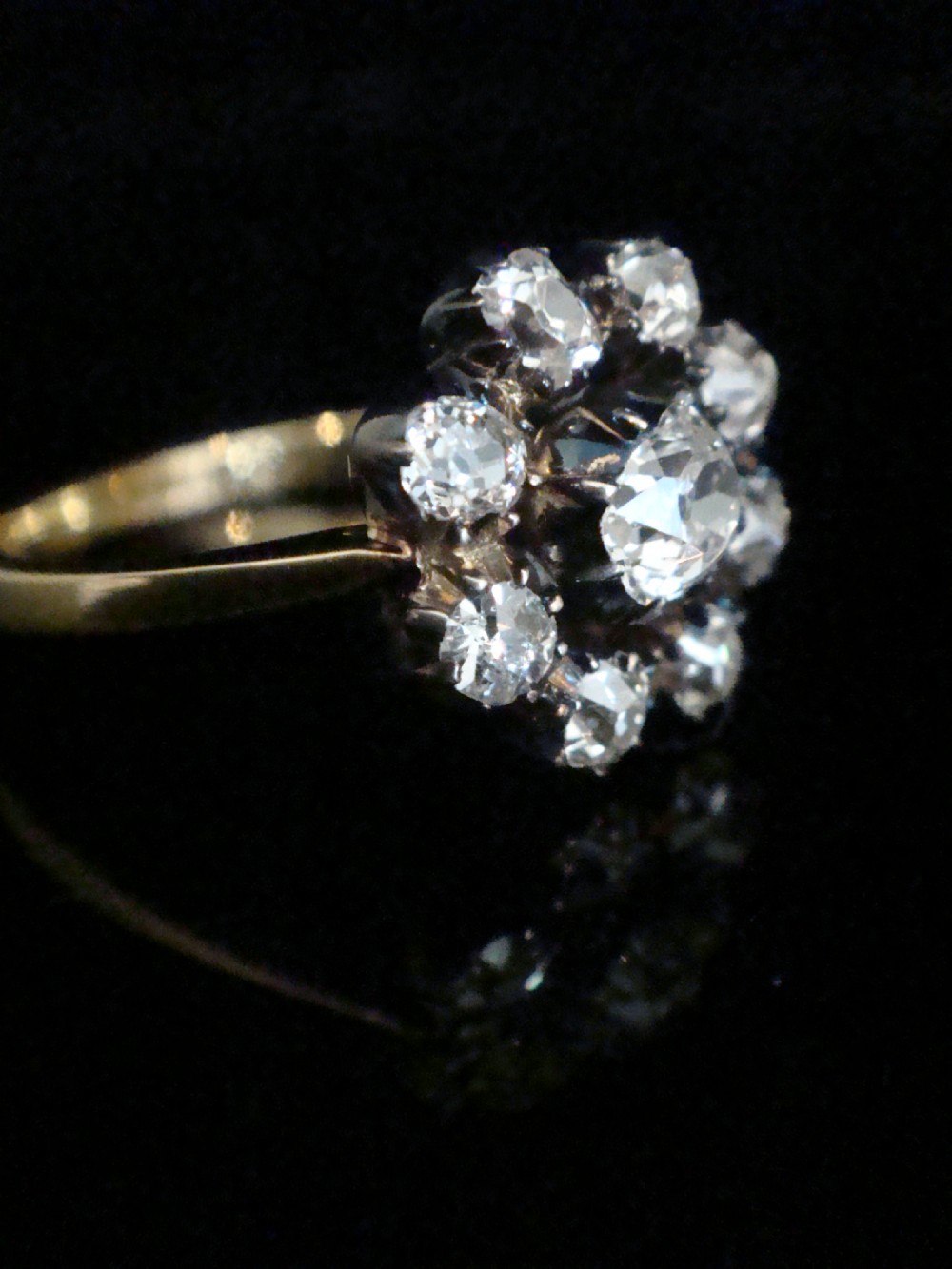 A Victorian 18ct yellow gold cluster ring featuring old mine cut diamonds arranged in a floral formation.