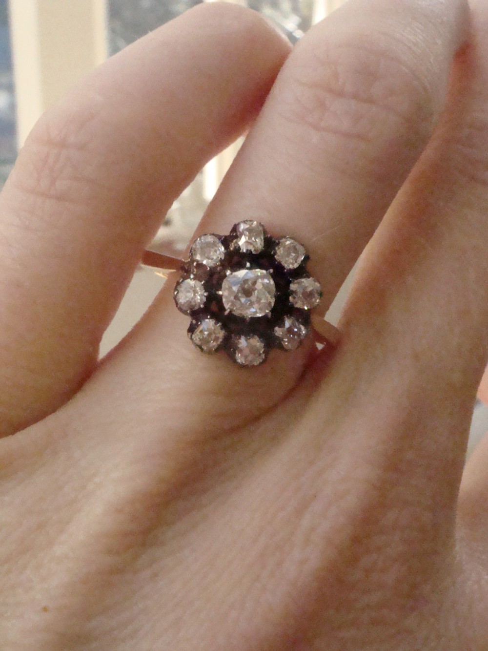 A Victorian 18ct yellow gold cluster ring featuring old mine cut diamonds arranged in a floral formation. View VI