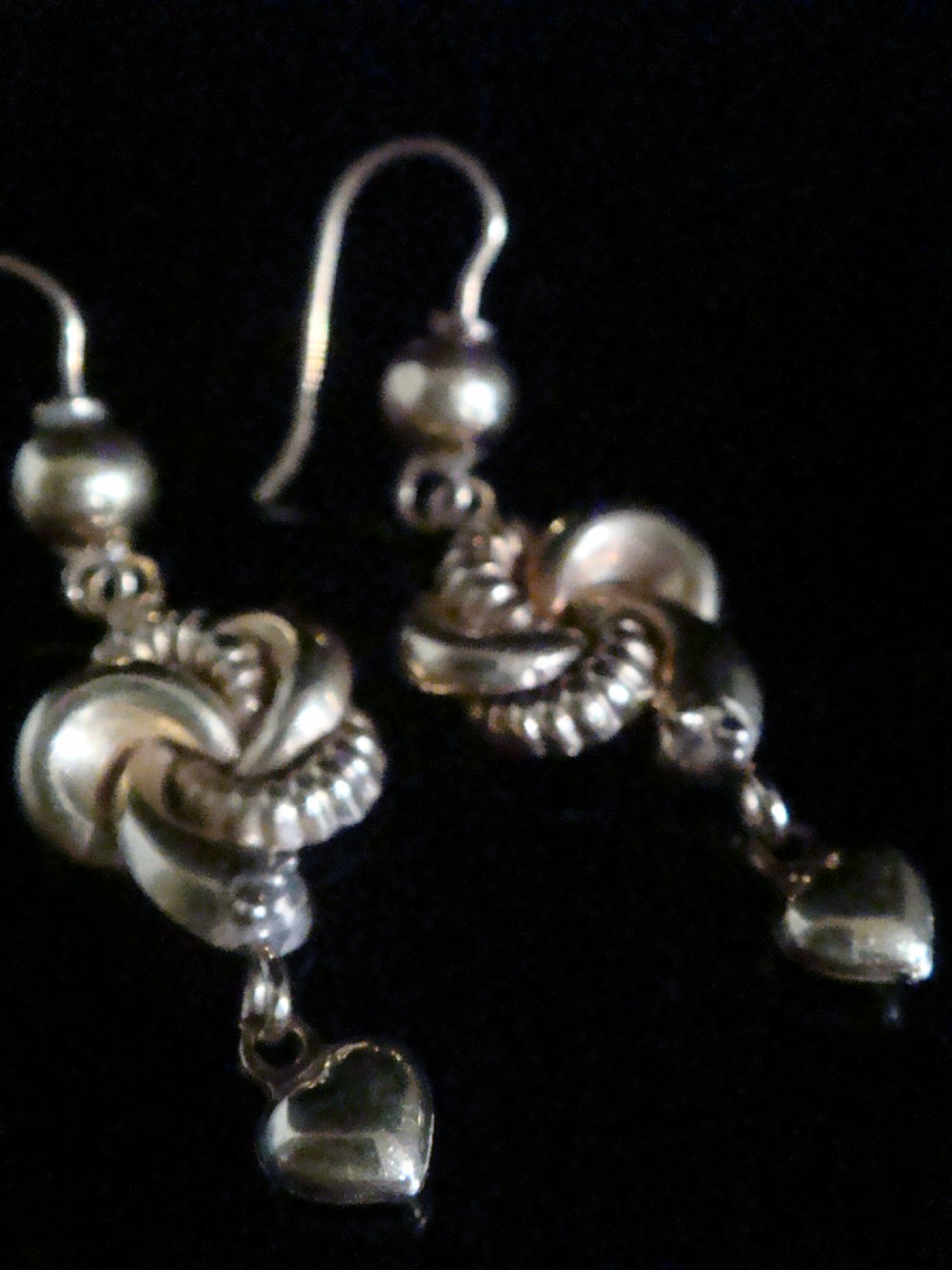 A pair of 9ct yellow gold drop earrings featuring an intertwined snake knot design suspended from shepherd hook fittings with dangling heart charms. View II