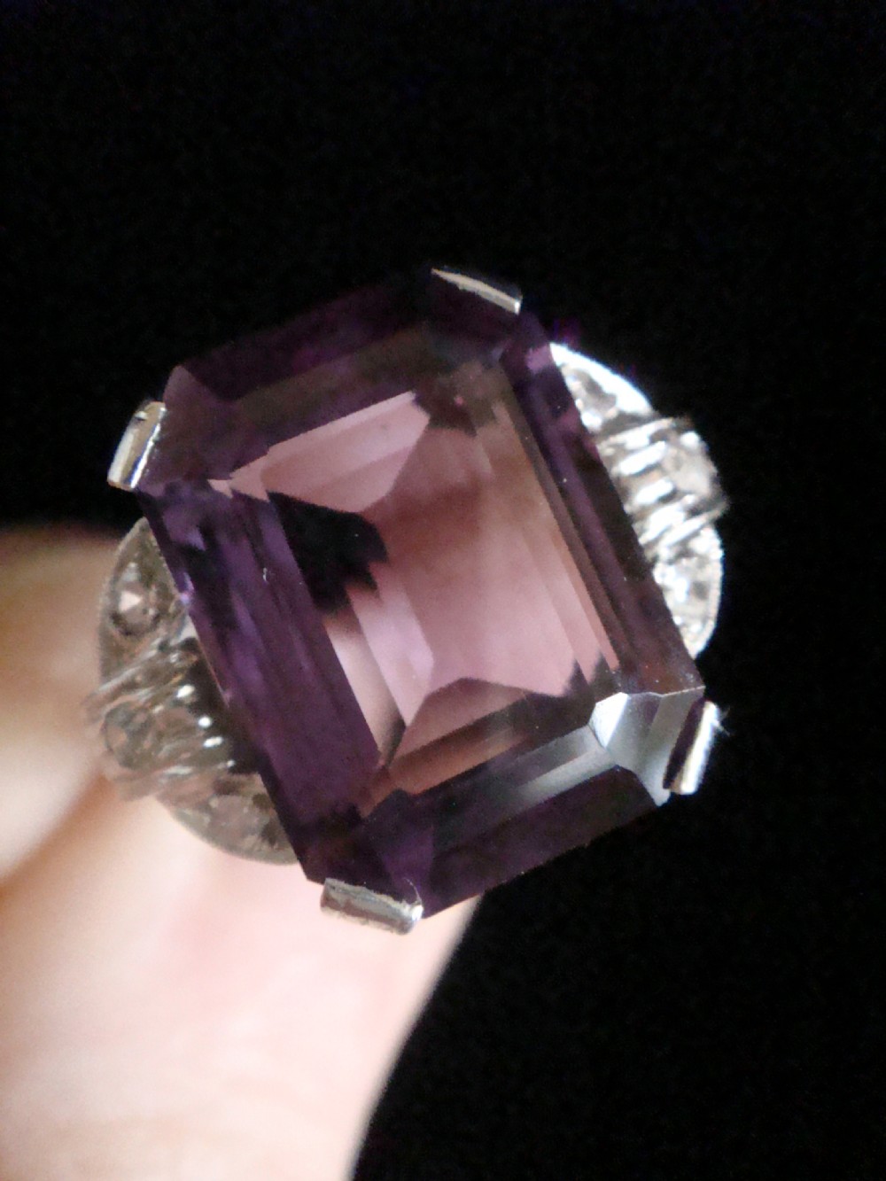 An Art Deco cocktail ring featuring a large emerald-cut purple amethyst flanked by diamond-set shoulders in an 18ct white gold setting. View IV