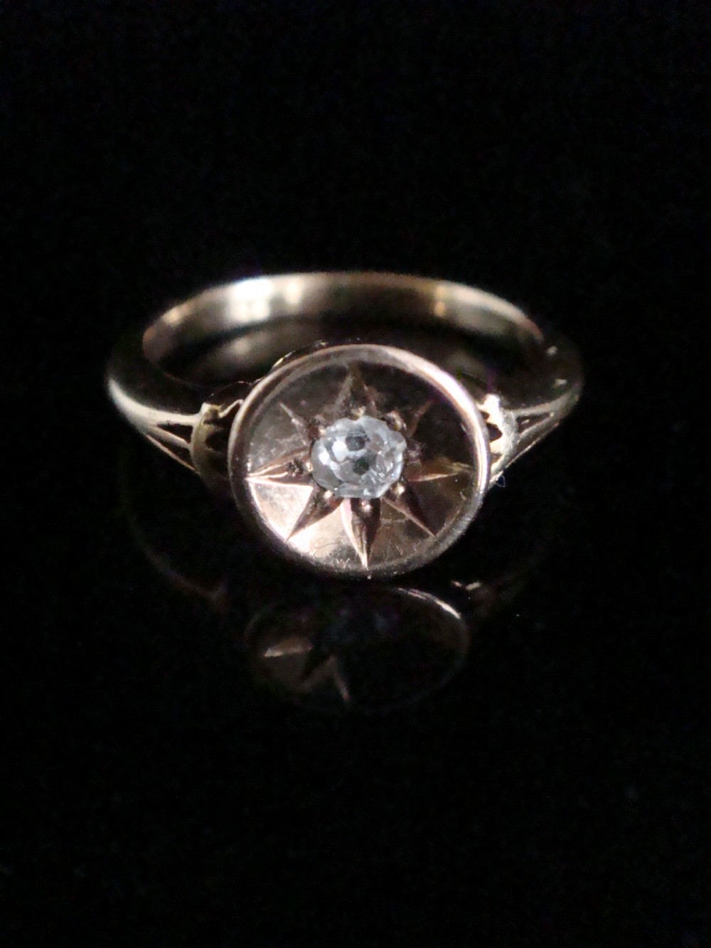 An 18ct yellow gold Victorian ring featuring a central starburst engraving with a single flush-set diamond.