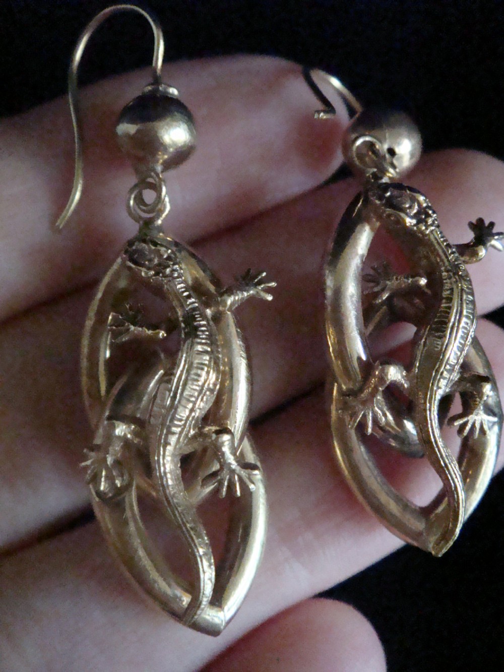 A pair of 9ct yellow gold drop earrings featuring sculpted three-dimensional lizards mounted over curved oval loops suspended from sphere studs. View VI
