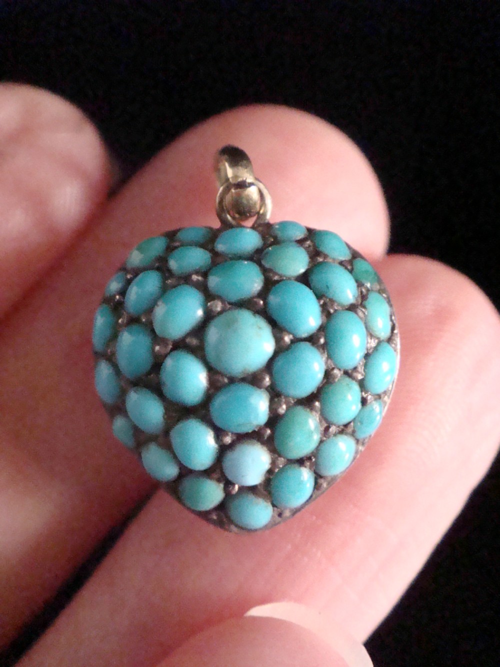A Victorian heart-shaped locket pendant heavily set with turquoise cabochon stones on a gold backing with a top suspension loop.