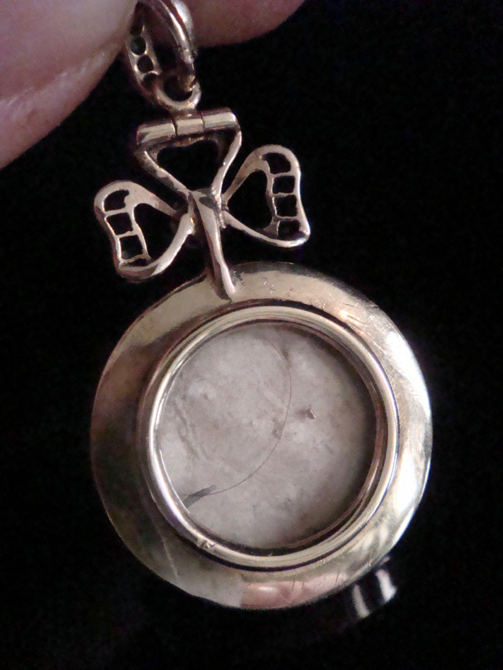 A circular Victorian gold locket featuring red guilloche enamel with a rose-cut diamond fleur-de-lis motif, surrounded by a white enamel border and topped with a diamond and pearl crown bail. View IV