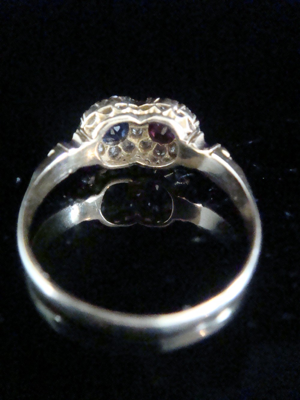 An Edwardian 18ct yellow gold Toi et Moi ring featuring a central ruby and sapphire, each encircled by a halo of old cut diamonds. View III